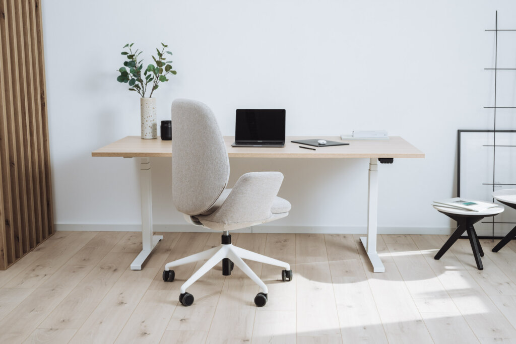 Heller höhenverstellbarer Schreibtisch im Home-Office und Bürostuhl